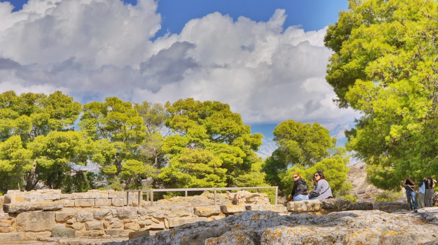 a group of people sitting on some rocks near trees