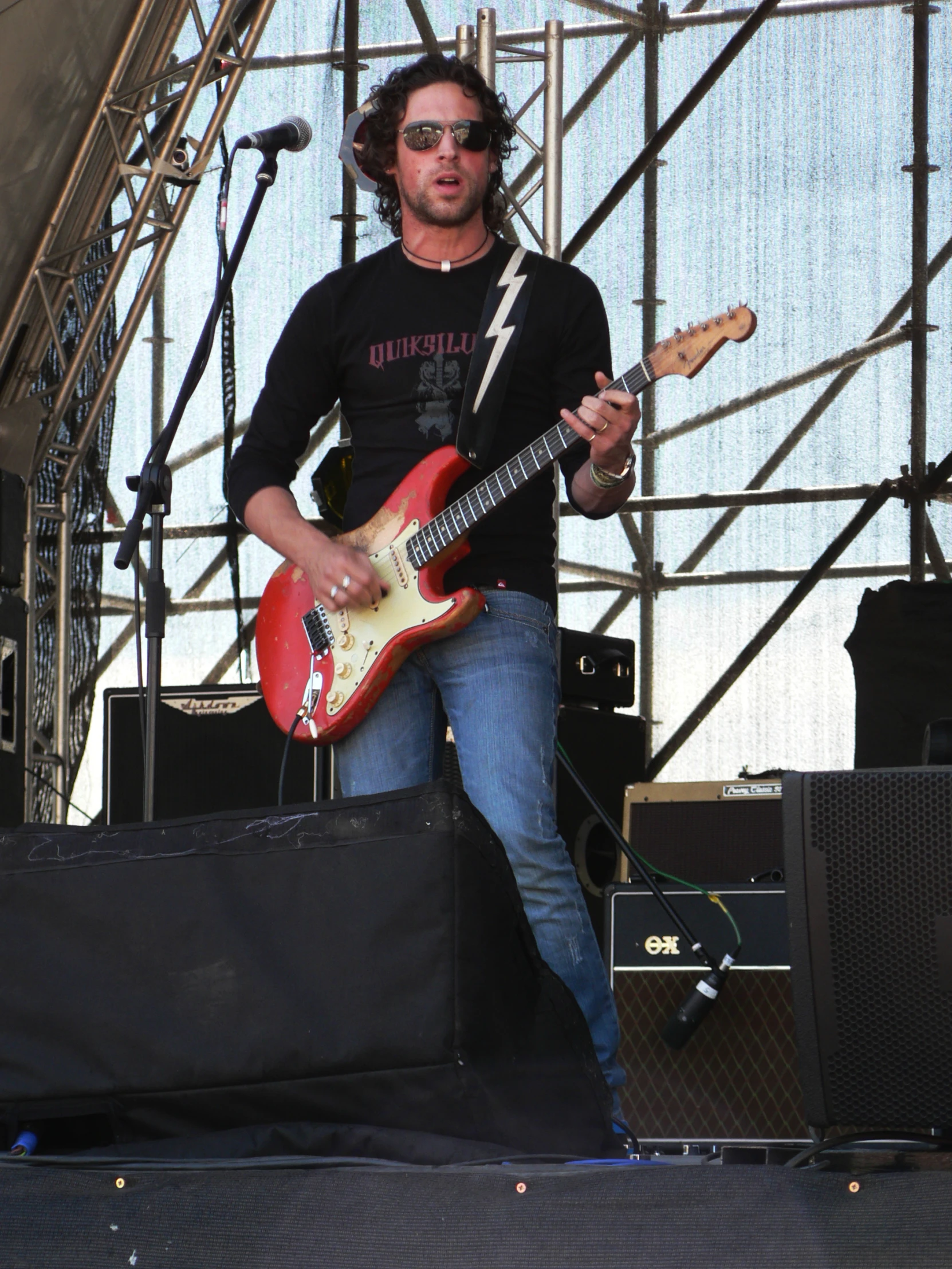 a man playing a guitar on stage during the day