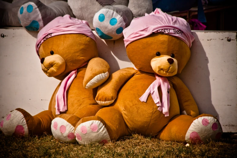 two large teddy bears sitting next to each other in front of a wall