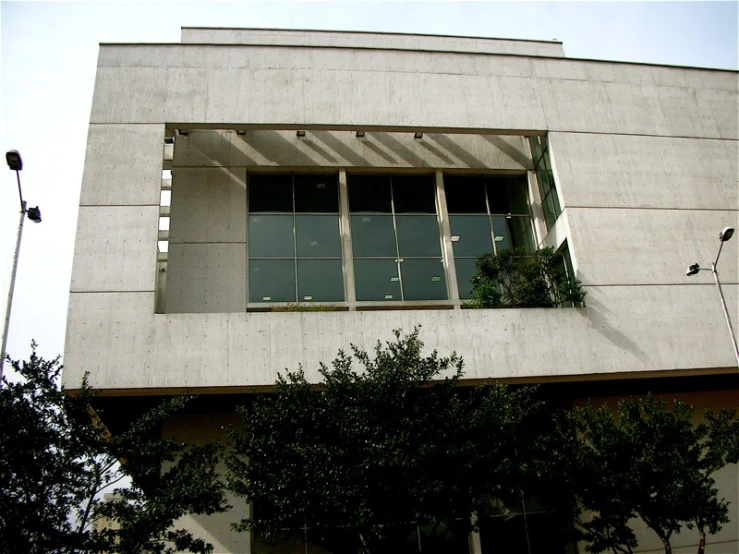 a concrete building with trees around the windows