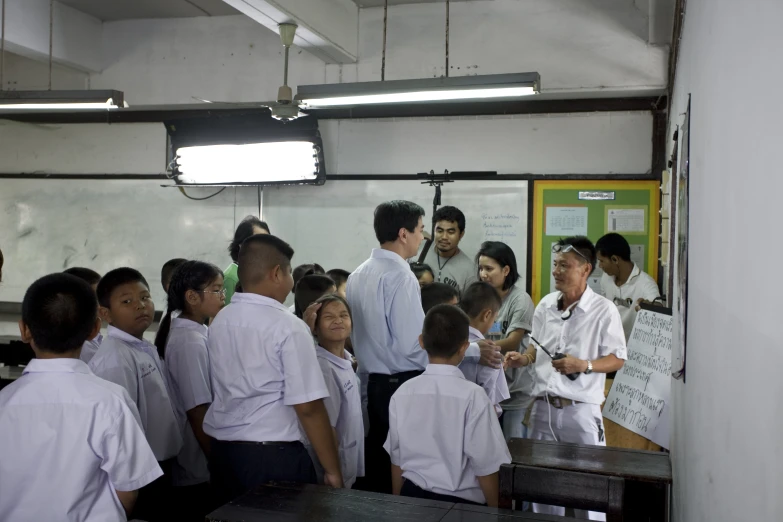 a group of school children are gathered around a man