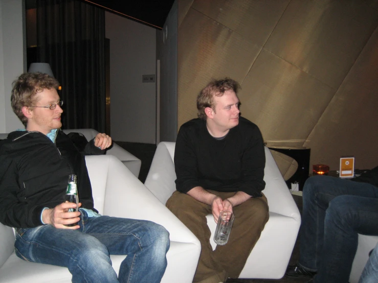 two men are sitting on couches while having drinks