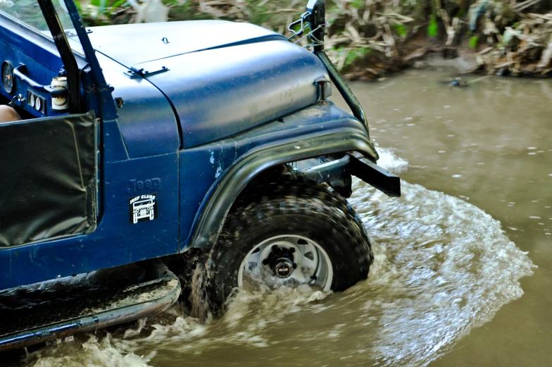 a jeep stuck in some water with it's wheels still on the ground