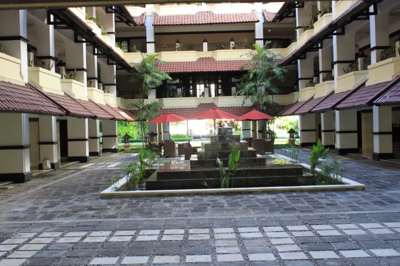 a courtyard area with tables and umbrellas inside of the building