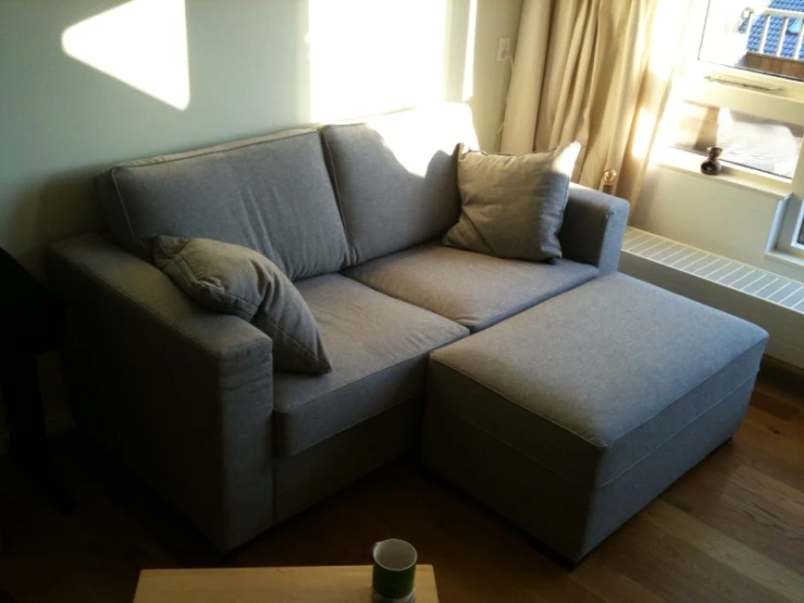 a couch is in front of the window, with a pillow sitting on it