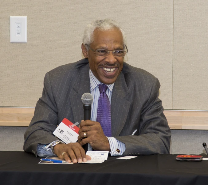 man smiling while speaking in front of a microphone