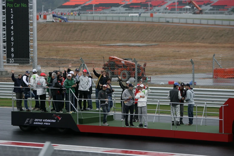 a race car with its flatbed carrying a bunch of fans