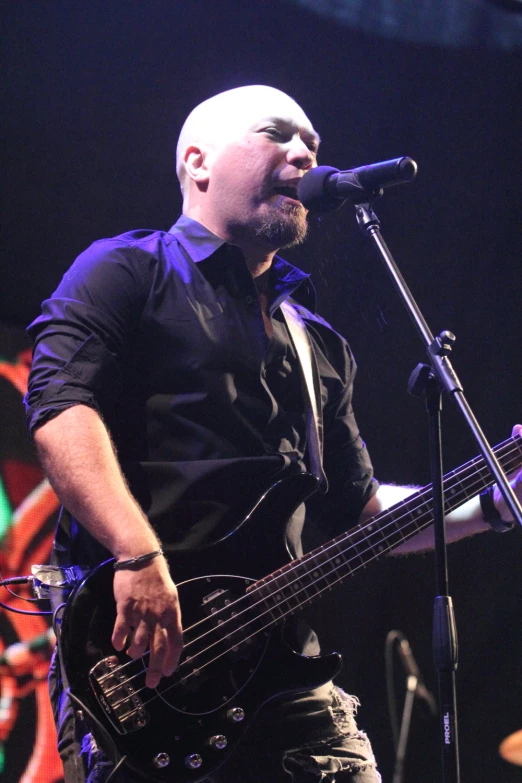 a man holding a bass guitar in front of microphone