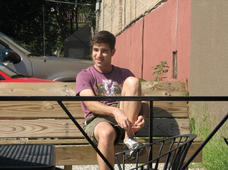 a guy sitting on a bench and smiling at the camera