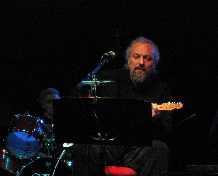 a man in black sitting down with a guitar