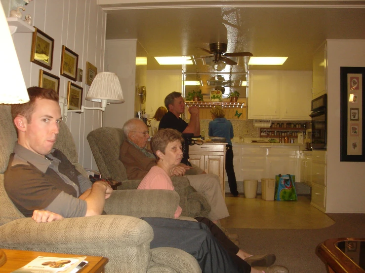 several people are sitting in the living room watching soing