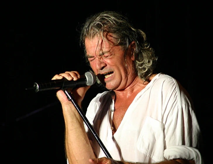 an older man is singing into a microphone