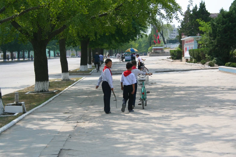 two people walking on the sidewalk next to trees and buildings