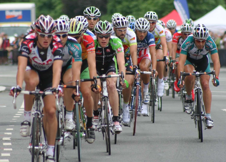 many people wearing bike clothing and helmets riding bicycles