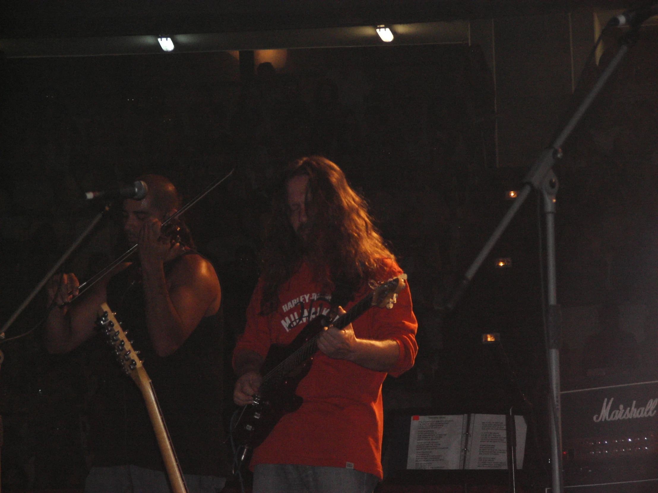 a man with long hair standing in front of another man on stage