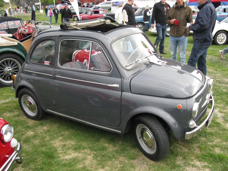 people stand near old fashion cars and their luggage