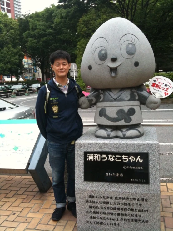 this man poses next to the monument dedicated to a cute character