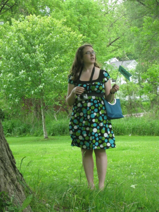 there is a woman in a polka dot dress walking by a tree