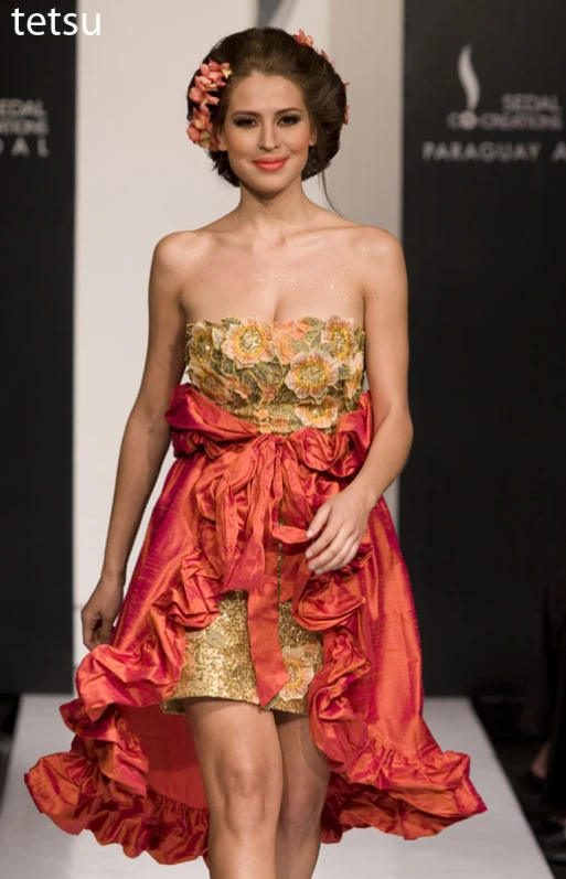 a women walking down the runway wearing an orange dress