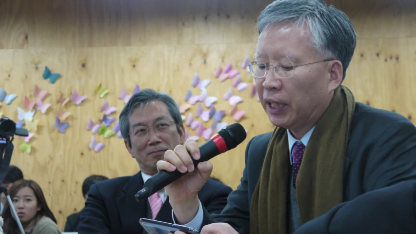 a man in a suit speaks into a microphone