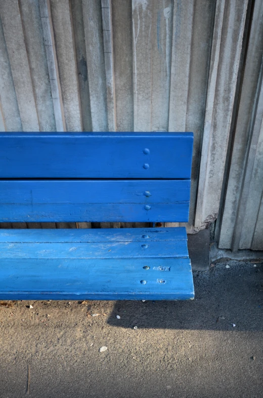 a bright blue bench near a wall