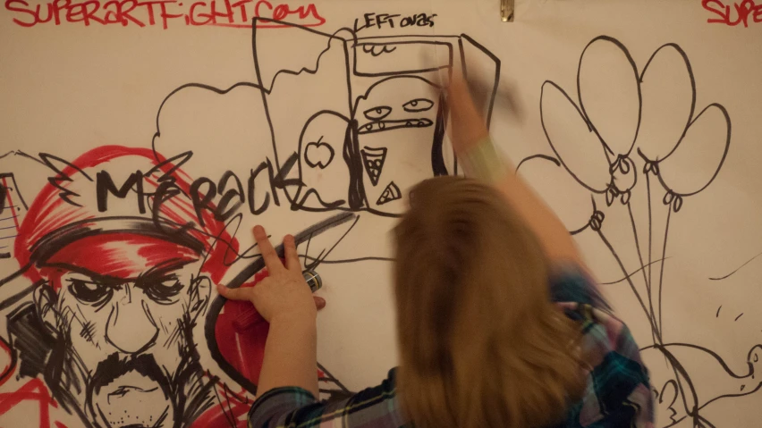 the woman is drawing on the wall of the house