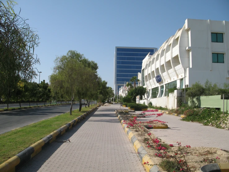 a road lined with flower and grass in front of a large building