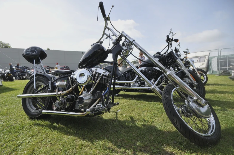 two chrome colored motorcycles sit on some grass