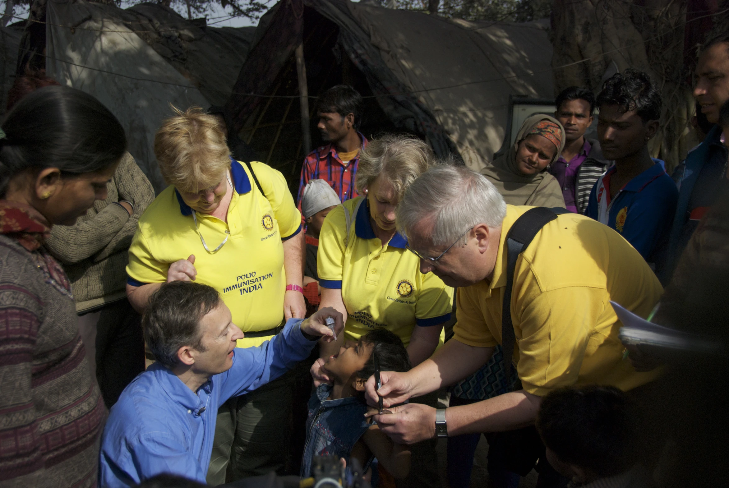 an older man showing a group of people how to brush their teeth