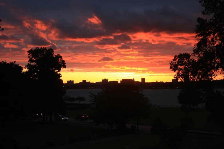 the sun rises over the water in the city park