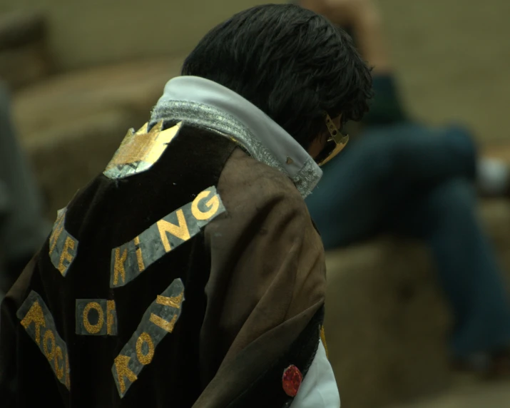 a boy wearing a brown and black jacket with some writing