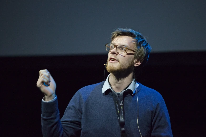 a man in blue sweater with his hand up in the air