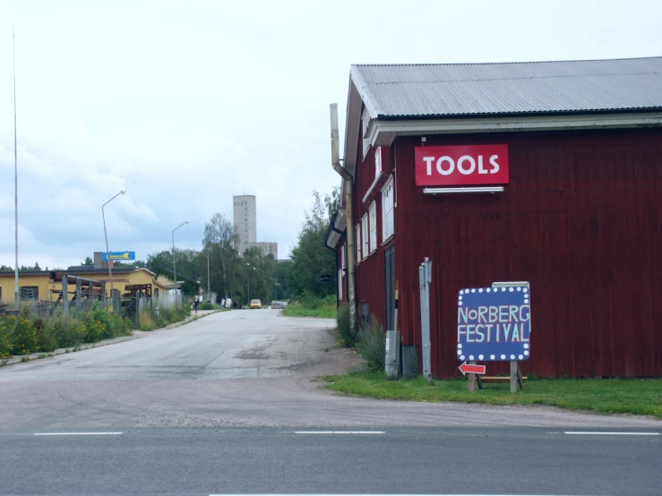 a red building with a banner and sign next to a small road