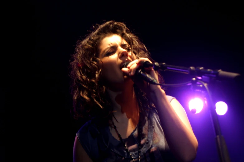 a woman singing into a microphone at night