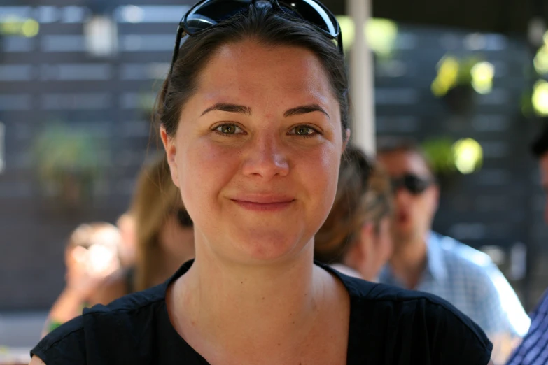 a woman smiling while wearing sunglasses at a party