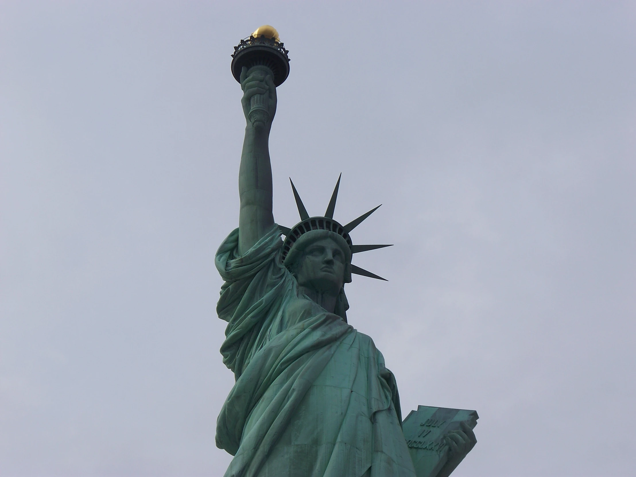 the statue of liberty holds the torch of liberty on a clear day