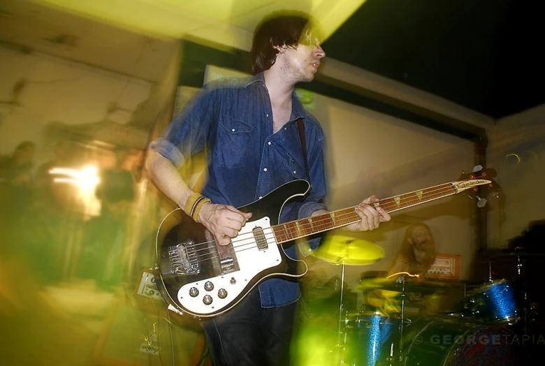 a young man plays the guitar while another young man watches