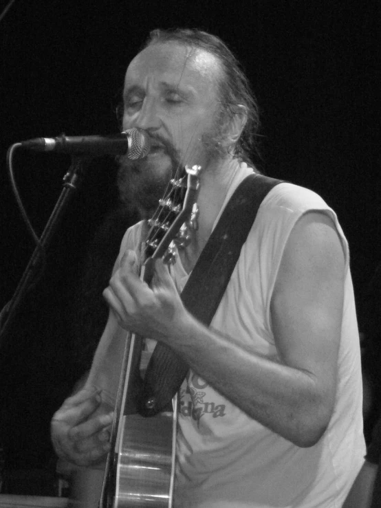 a man singing into a microphone and playing a guitar