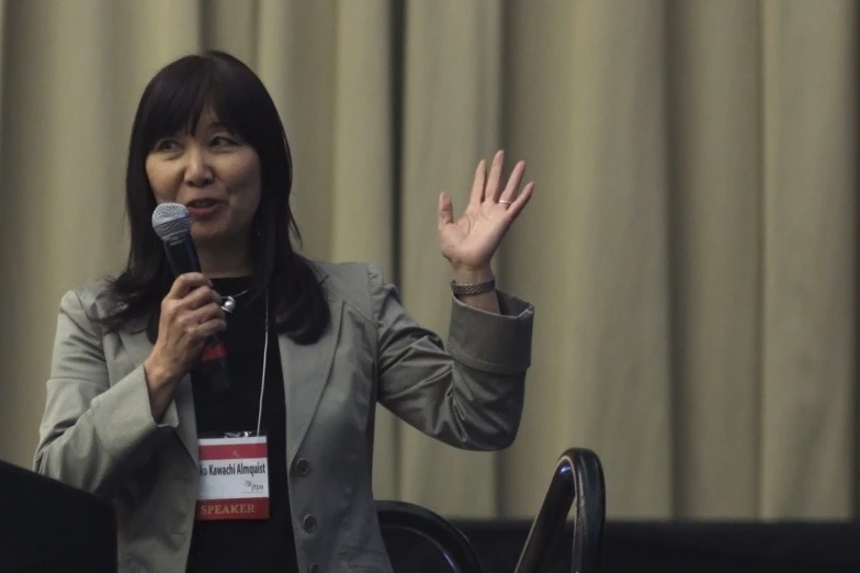 an asian woman in a business suit holding a microphone