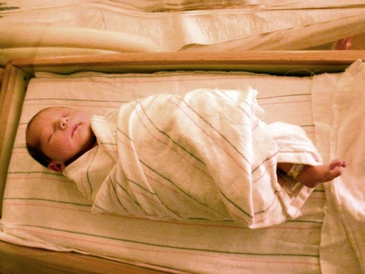 a small child sleeping in a crib with a blanket