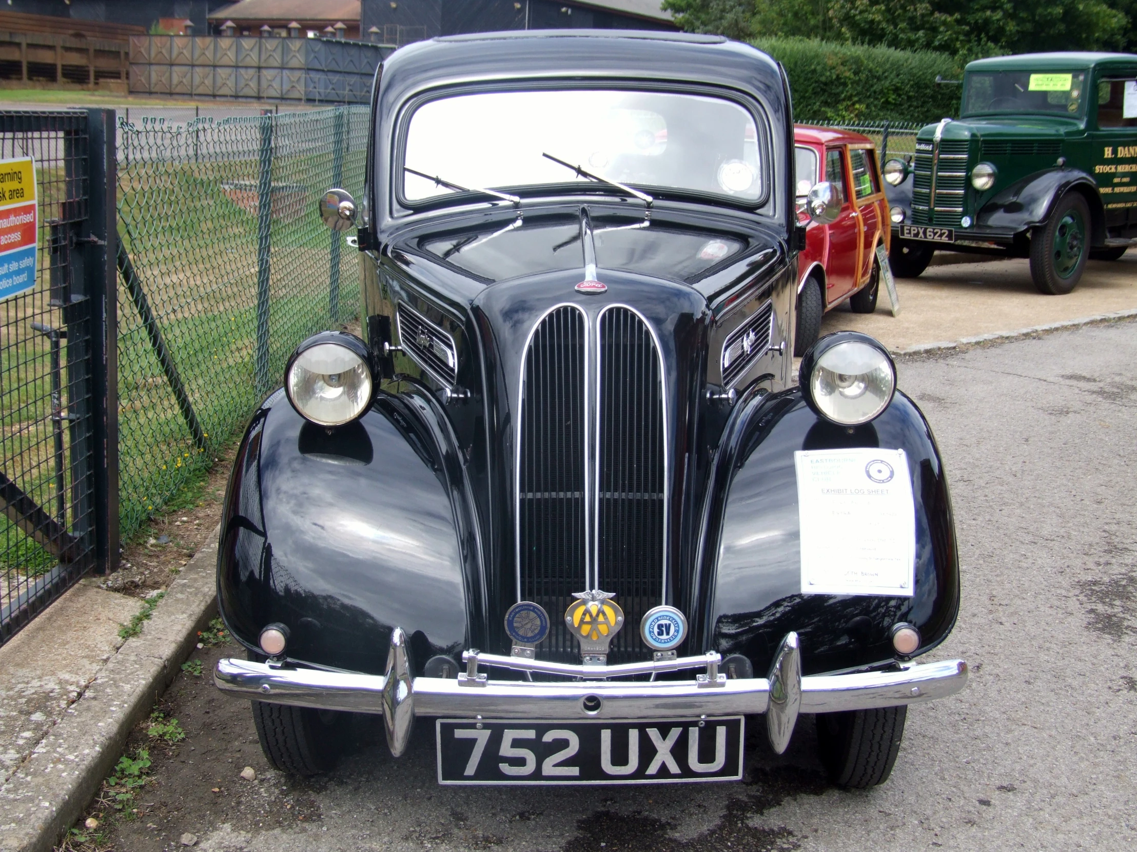 a old black car is parked behind a fence