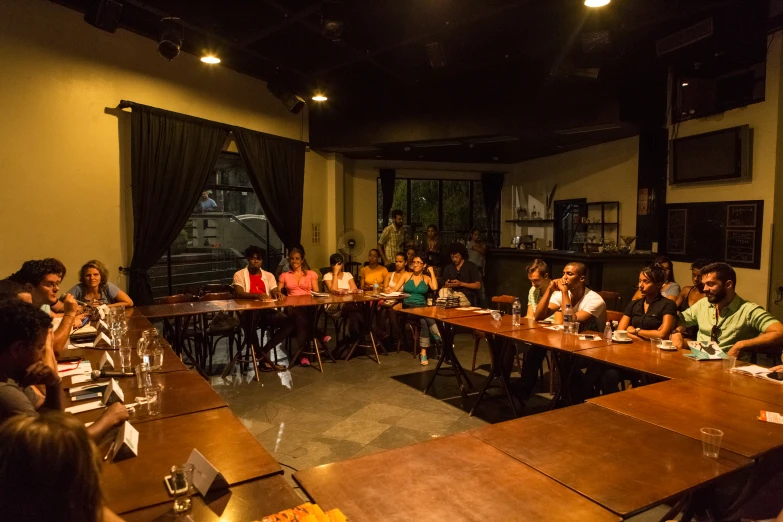 a long table full of people are waiting for a presentation