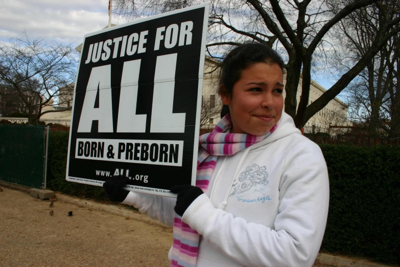 a woman holding up a sign with some writing on it