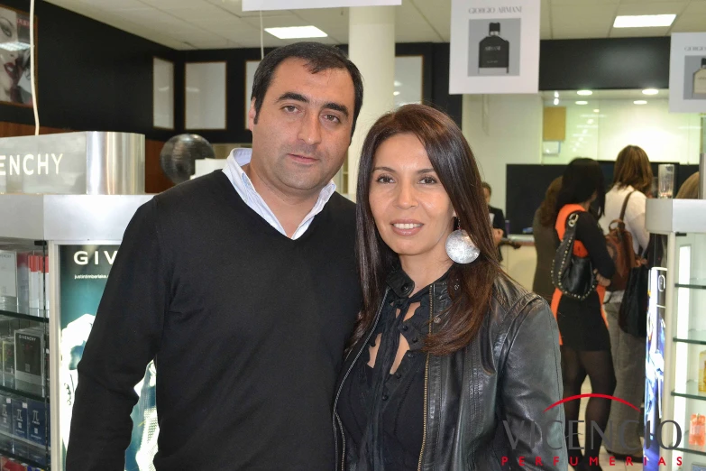 a man and woman stand in front of a store window