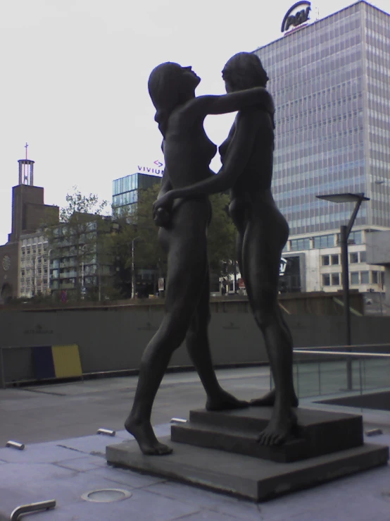 statue of two people touching each other and in front of building