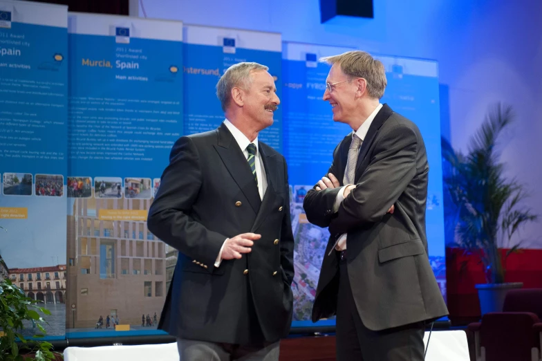 two men are smiling as they stand by each other