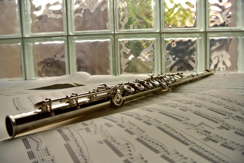 an old silver flute lying on a sheet music