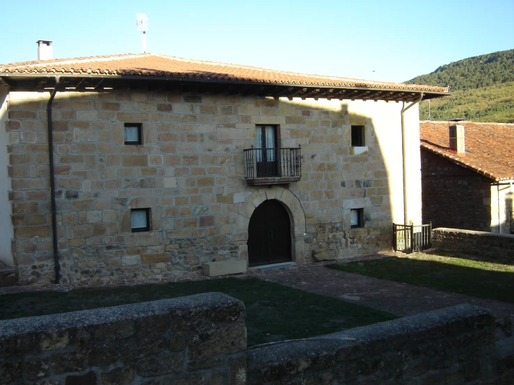 an old stone building with no doors is next to the hillside