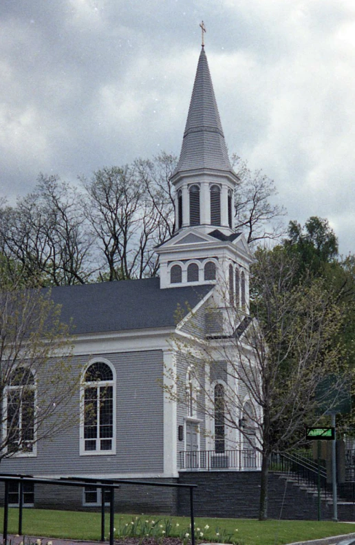 a church sits next to a sidewalk and trees