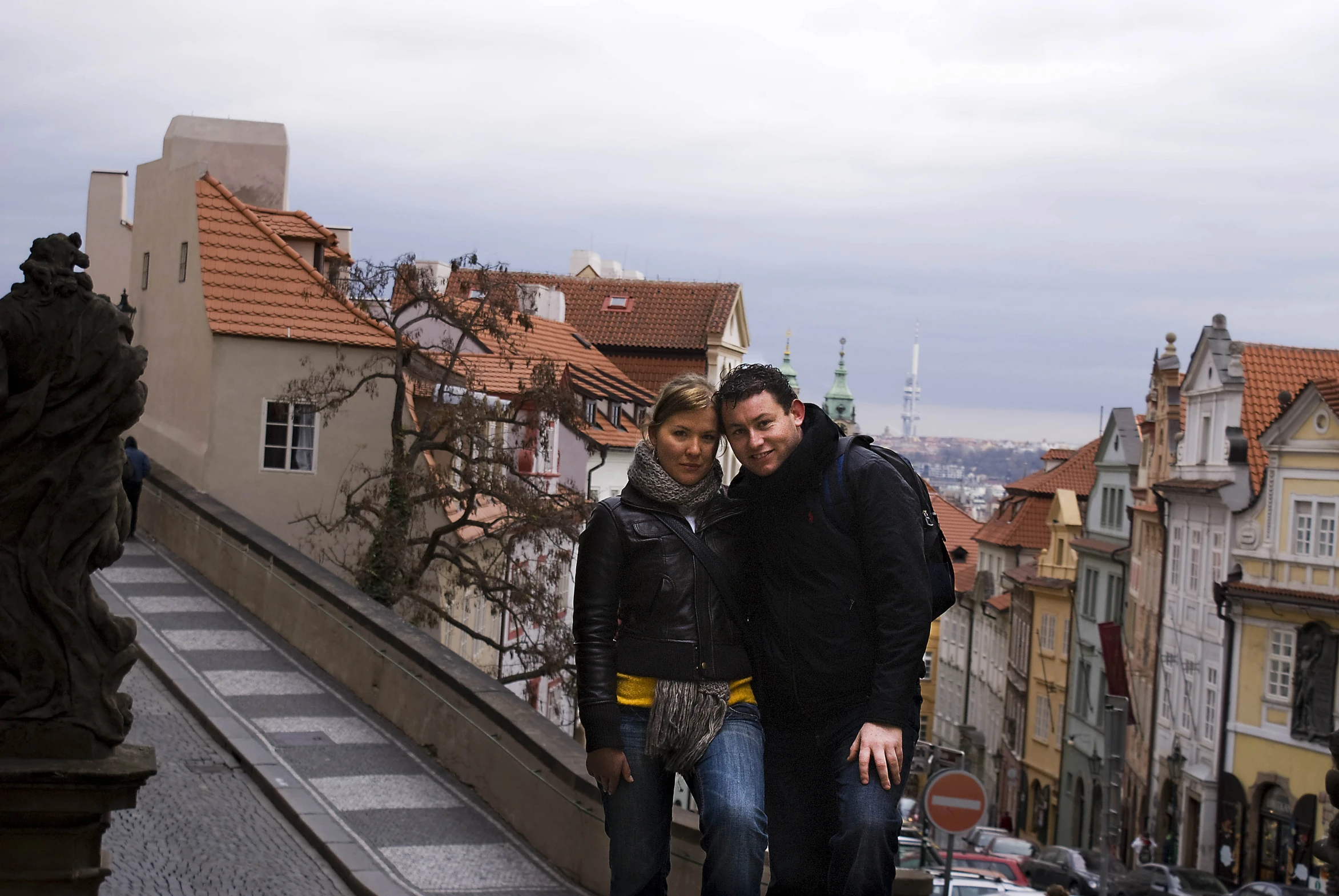 two people stand on the top of a balcony near buildings